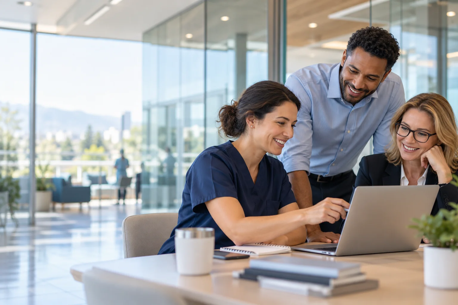 Healthcare technology colleagues collaborating around a laptop in a bright hospital office